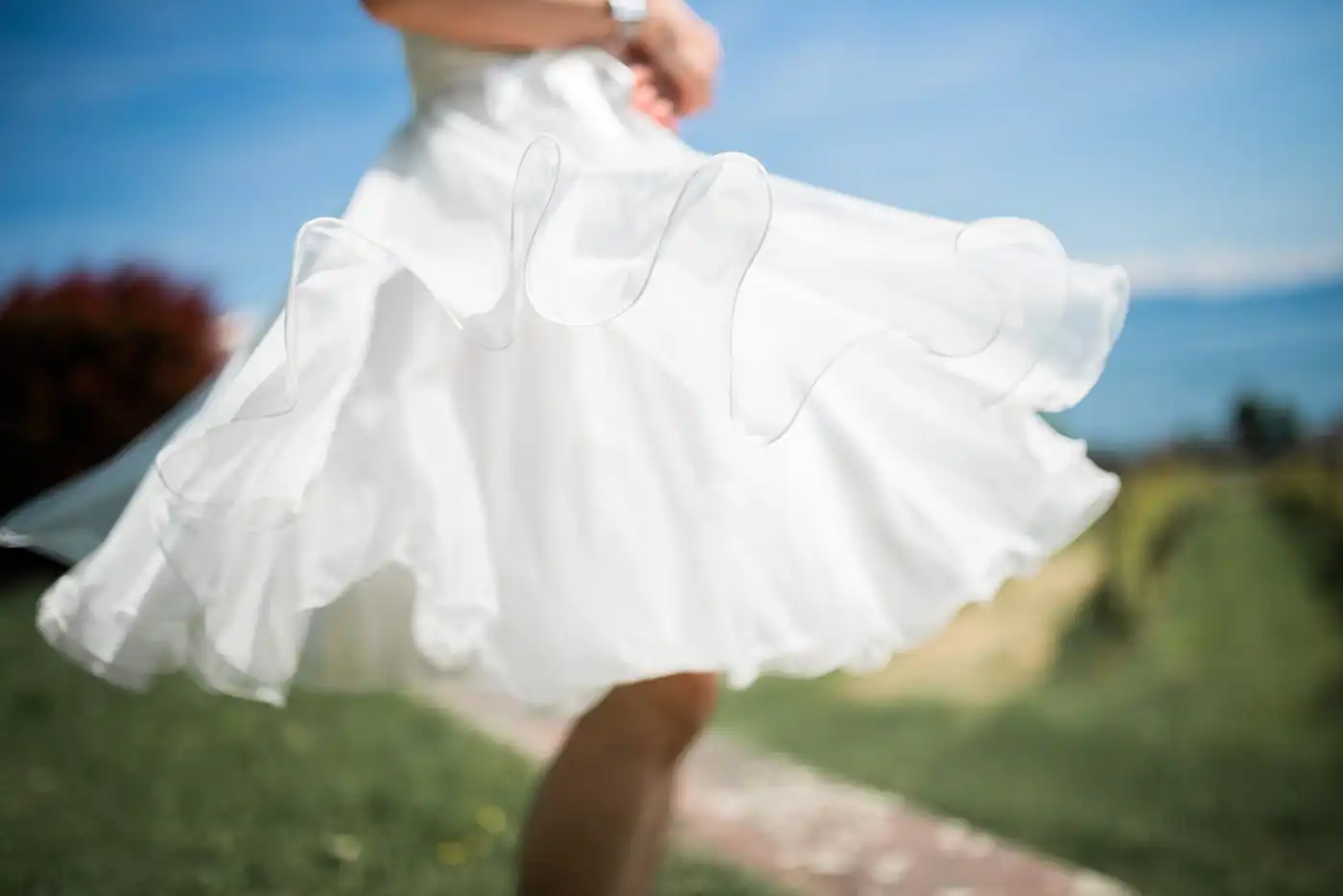 A bride’s skirt caught by the wind on the walk up to a lakeside ceremony